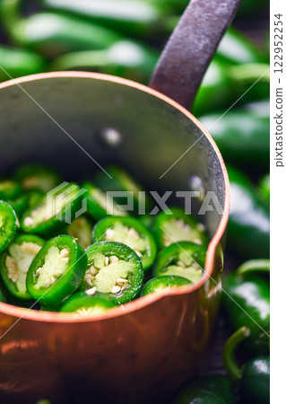 Copper ladle filled with sliced green mexican jalapeno Copper ladle filled with sliced green mexican jalapeno 122952254