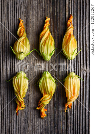 Fresh zucchini flowers on rustic wooden table close up Fresh zucchini flowers on rustic wooden table close up 122952267