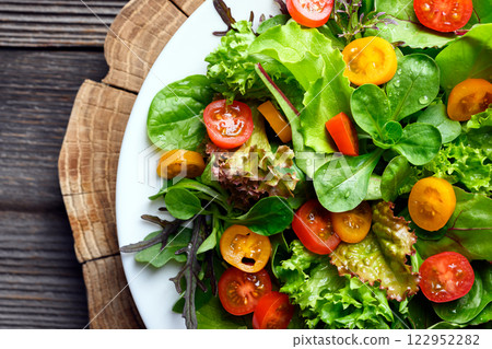 Mix of fresh organic juicy salad greens with red and yellow cherry tomatoes 122952282