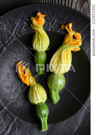 Young fresh zucchini with flowers in black plate 122952302