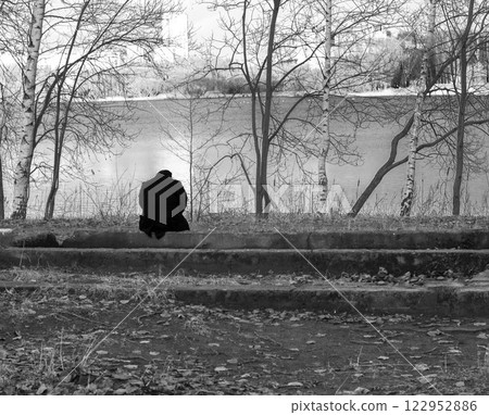 Conceptual, black and white shot of the person sitting by the bank of the river 122952886