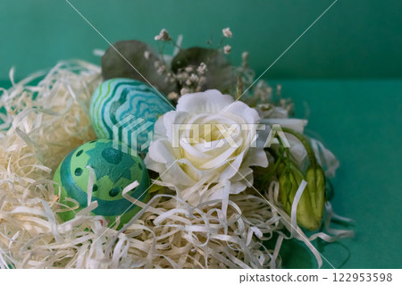 Side view of painted eggs and flowers in green background 122953598