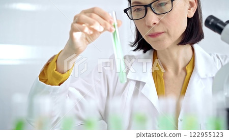 Scientist examining lab tube with a green fluid. Microbiology and science concept Scientist examining lab tube with a green fluid. Microbiology and science concept 122955123