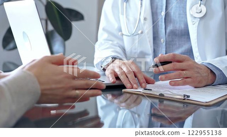 Doctor and patient conversation with clipboard in clinic office. Physician is making notes while listening woman. Medicine and Health care Doctor and patient conversation with clipboard in clinic office. Physician is making notes while listening woman. Medicine and Health care 122955138