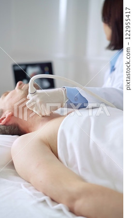 Doctor performing neck ultrasound exam on male patient Doctor performing neck ultrasound exam on male patient 122955417
