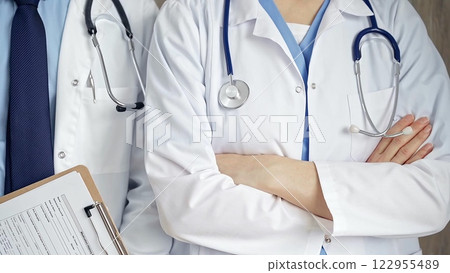 Professional healthcare team in uniform. Two doctors with stethoscopes are standing straight with arms crossed. Medicine concept Professional healthcare team in uniform. Two doctors with stethoscopes are standing straight with arms crossed. Medicine concept 122955489