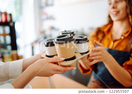 Young woman owner of a coffee shop behind the bar prepares coffee. Concept of orders to go. 122955507