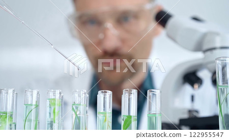 Man researcher with safety glasses is working with lab tubes using a pipette in laboratory, close-up of lab equipment. Science and medicine 122955547