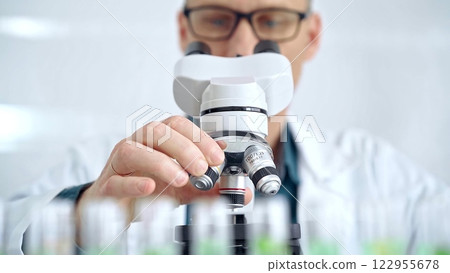 Man scientist with protective glasses using microscope in laboratory. Microbiology science concept 122955678
