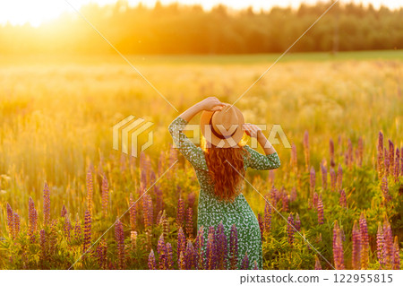 A beautiful woman with a bouquet of lupins, collects flowers, inhales fresh floral air. A beautiful woman with a bouquet of lupins, collects flowers, inhales fresh floral air. 122955815