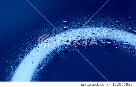 Texture of splashed water on illuminated blue glass surface 122955922