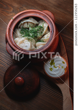 Hot, juicy dumplings snuggled in a pot. Next to it 122956263
