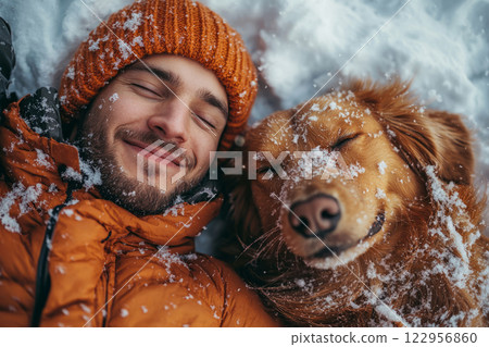 Smiling man and happy dog lying in snow on winter day 122956860