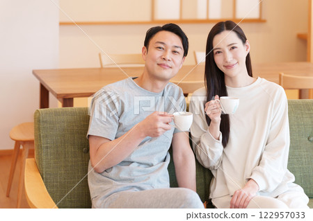 A couple waking up in the morning and drinking coffee in the living room 122957033
