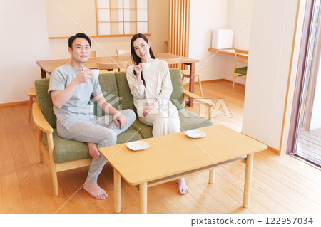 A couple waking up in the morning and drinking coffee in the living room A couple waking up in the morning and drinking coffee in the living room 122957034