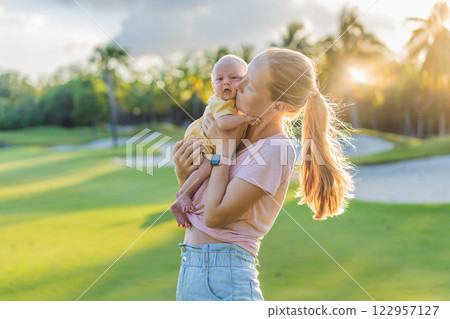 Young mother enjoying a peaceful walk in the park with her one-month-old baby. Motherhood, bonding, and outdoor family time concept 122957127