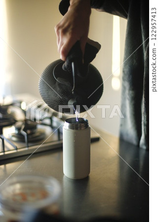 Pouring boiled water from an iron kettle into a water bottle Pouring boiled water from an iron kettle into a water bottle 122957413