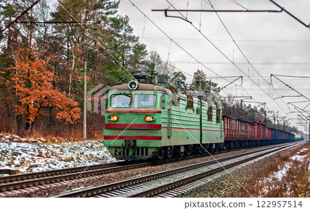 Old Soviet electric locomotive with a heavy freight train in winter in Kyiv Oblast of Ukraine 122957514