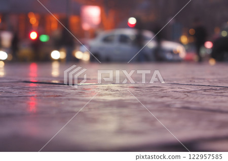 Raindrops reflect street lights on a wet urban pavement at dusk Raindrops reflect street lights on a wet urban pavement at dusk 122957585