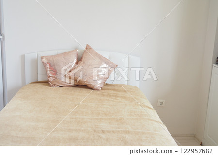 Cozy bedroom with golden accents and decorative pillows 122957682