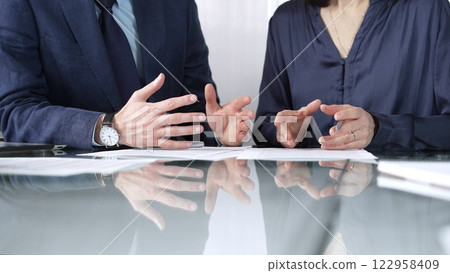 Business people reviewing contract terms while sitting at the glass desk during a meeting, negotiation in office, close up view. Success concept Business people reviewing contract terms while sitting at the glass desk during a meeting, negotiation in office, close up view. Success concept 122958409