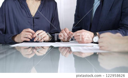 Business people reviewing contract terms while sitting at the glass desk during a meeting, negotiation in office, close up view. Success concept 122958626