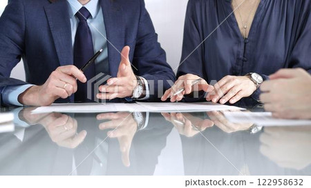 Business partners or lawyers are discussing contract papers during a meeting, negotiating and making decisions together. Business people concept, close up 122958632