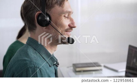 Focused male call center operator in green casual shirt is assisting clients online, providing customer support and answering inquiries. Call center concept Focused male call center operator in green casual shirt is assisting clients online, providing customer support and answering inquiries. Call center concept 122958661