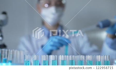 Laboratory tubes are in focus, closeup view. Female scientist researcher is using a micropipette at the background. Medicine and science Laboratory tubes are in focus, closeup view. Female scientist researcher is using a micropipette at the background. Medicine and science 122958715