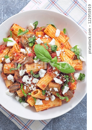 Rigatoni alla Norma pasta with eggplant, tomato, basil and ricotta salata, horizontal top view 122958919