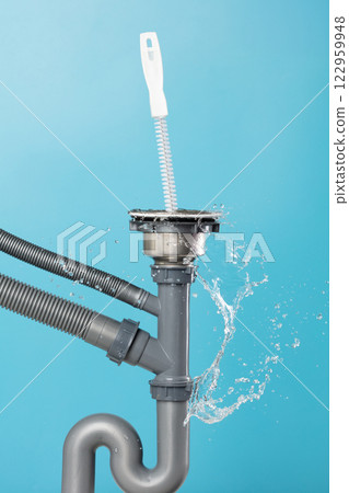 Drain sink leak water from pipe plumbing in kitchen bathroom as water splash clogged drop. Pouring Leaking water from gray plastic pipe drain sink by probe cable. Blue background isolated 122959948