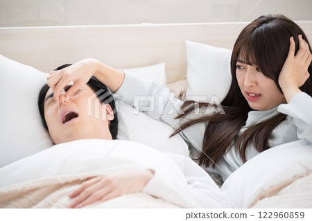 A woman who couldn't sleep because her husband or partner's snoring was so loud she pinched her nose 122960859