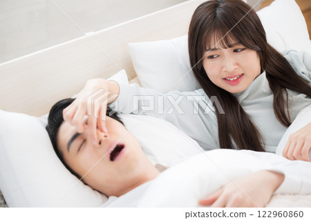 A woman who couldn't sleep because her husband or partner's snoring was so loud she pinched her nose 122960860