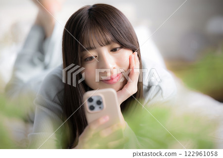 特寫鏡頭：一位年輕女子躺著看她的智慧型手機 122961058