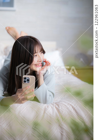 特寫鏡頭:一位年輕女子躺著看她的智慧型手機 特寫鏡頭:一位年輕女子躺著看她的智慧型手機 122961063