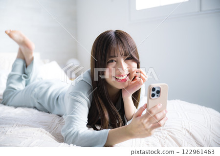 女人躺著，用智慧型手機看相機，全身 122961463
