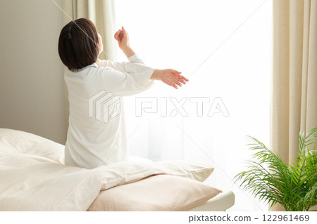 一名身穿睡衣的中年婦女清晨在臥室伸展身體 122961469