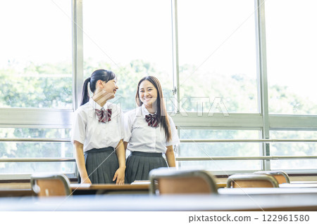 兩個高中女生在課堂上和朋友聊天 兩個高中女生在課堂上和朋友聊天 122961580