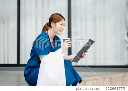 Asian woman part time doctorRepresentation of the daily life of a nurse going to work. Young, confident nurse outside looking away with smile on her face. 122961755