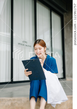 Asian woman part time doctorRepresentation of the daily life of a nurse going to work. Young, confident nurse outside looking away with smile on her face. 122961757
