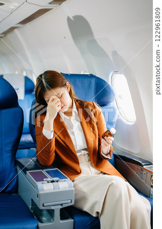 Photo of a frustrated woman sitting on an airplane with her head in her hands Photo of a frustrated woman sitting on an airplane with her head in her hands 122961809