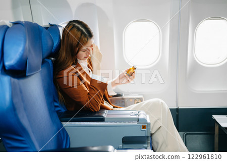 Photo of a frustrated woman sitting on an airplane with her head in her hands Photo of a frustrated woman sitting on an airplane with her head in her hands 122961810