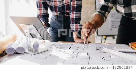 Creative architect projecting on the big drawings in the dark loft office or cafe in morning light Creative architect projecting on the big drawings in the dark loft office or cafe in morning light 122961884