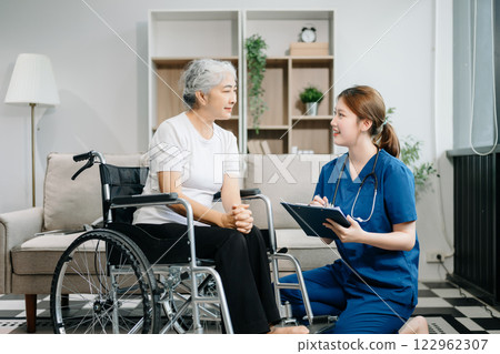 Asian caregiver doctor examine older patient use blood pressure gauge. woman therapist nurse at nursing home taking care of senior elderly woman sit on sofa Asian caregiver doctor examine older patient use blood pressure gauge. woman therapist nurse at nursing home taking care of senior elderly woman sit on sofa 122962307