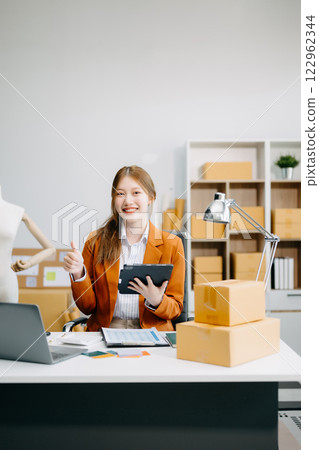 Young business owner woman prepare parcel box and standing check online orders for deliver Young business owner woman prepare parcel box and standing check online orders for deliver 122962344