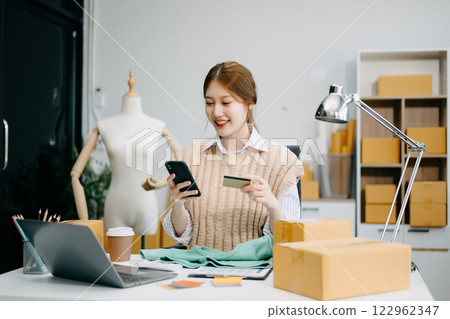 Young business owner woman prepare parcel box and standing check online orders for deliver 122962347