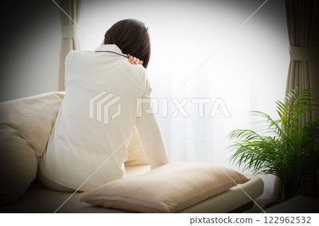 一名身穿白色睡衣的中年婦女早上在臥室裡感到肩膀僵硬 122962532