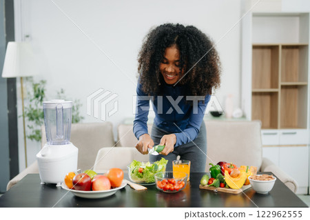 A fit woman enjoys a fresh salad with fruits and juice, embodying wellness, nutrition, and vitality 122962555