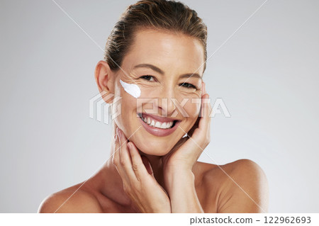 Cream, face wellness and mature woman with skincare product for health against a grey mockup studio background. Portrait of model with smile and happy about dermatology sunscreen with mock up space 122962693