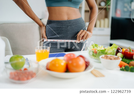 Smiling woman measuring waist, holding green apple with fruits, veggies, 122962739